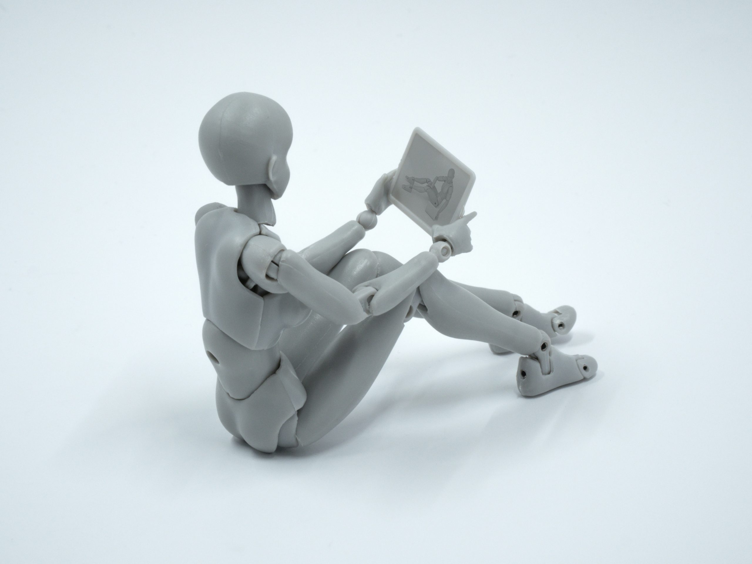 A white plastic mannequin holding a tablet with another mannequin on it, used to depict advice from digital media live streaming specialists Inner Ear for which video conferencing tool to use for remote participation in events.